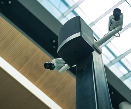 Two white security cameras on a black pillar in the airport premises