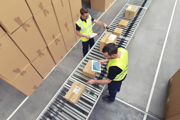 Worker in a warehouse in the logistics sector processing packages on the assembly line