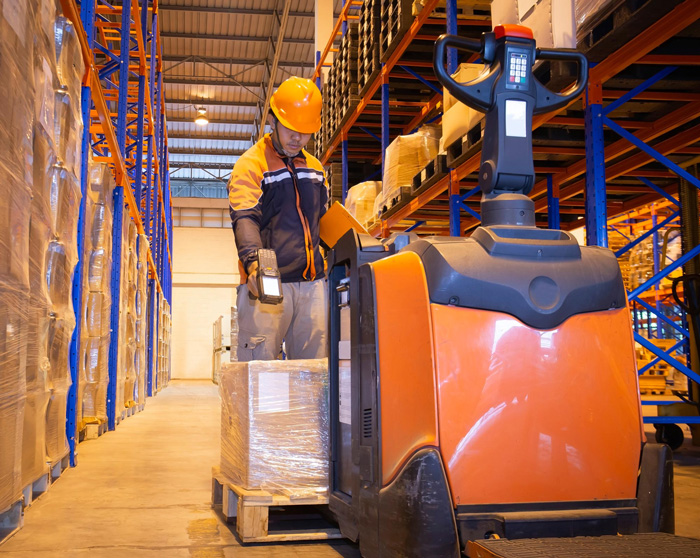 warehouse worker is scanning bar code scanner with goods pallet and electric forklift pallet jack