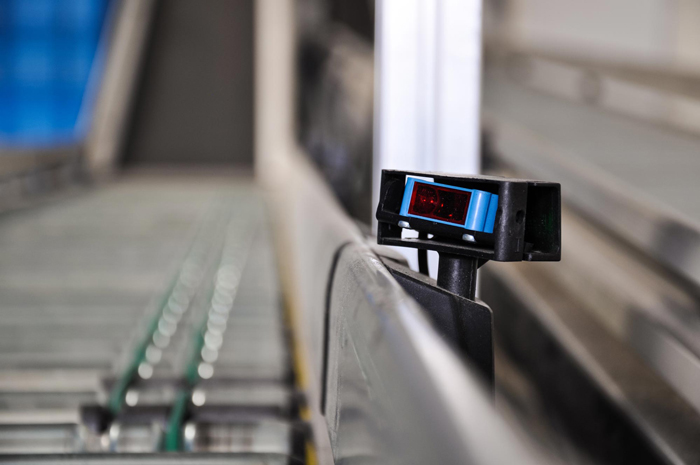 Close up shot of a roller conveyor with a laser distance sensor on the side